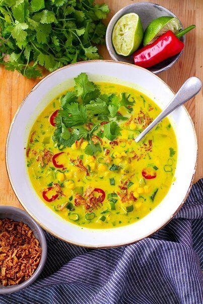 Тёплый кремовый суп из цукини и кукурузы, украшенный зелёной кинзой и ломтиками острого перца