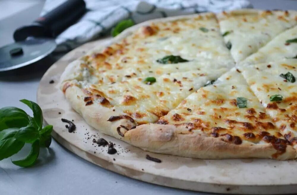 Белая пицца - сервировка, кусочки с тянущимся сыром